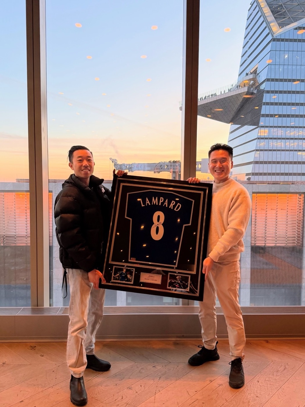 Two teammates with a framed jersey at sunset